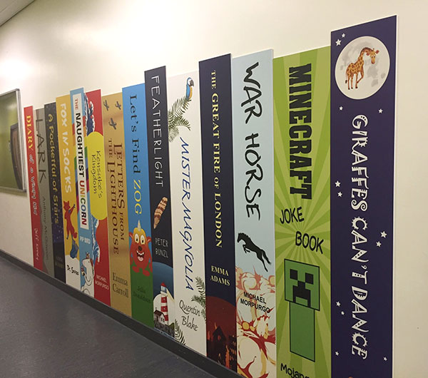 Book spine graphics displayed on a school wall