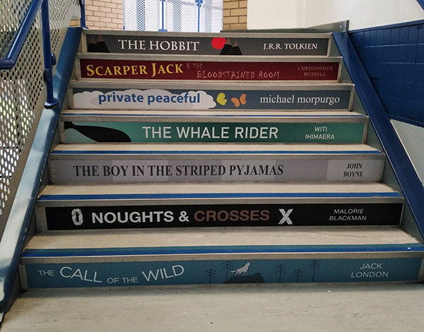 Book spine stair graphics on the risers of steps in a school