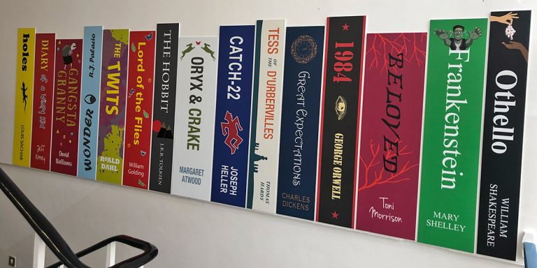 Book spine wall graphics on stairwell wall at a school