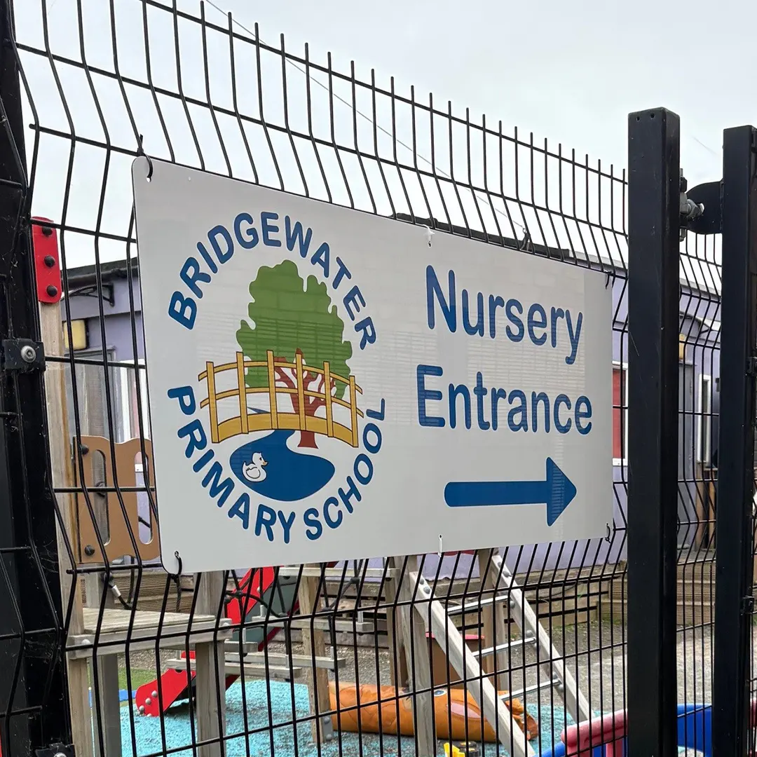 Nursery entrance sign fixed to a fence to direct parents to the Nursery at the Primary School.