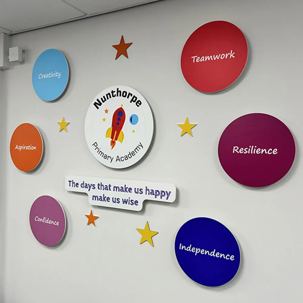 Bespoke school values signage wall display for Nunthorpe Primary Academy, featuring a central logo, six circular value signs, and scattered stars.