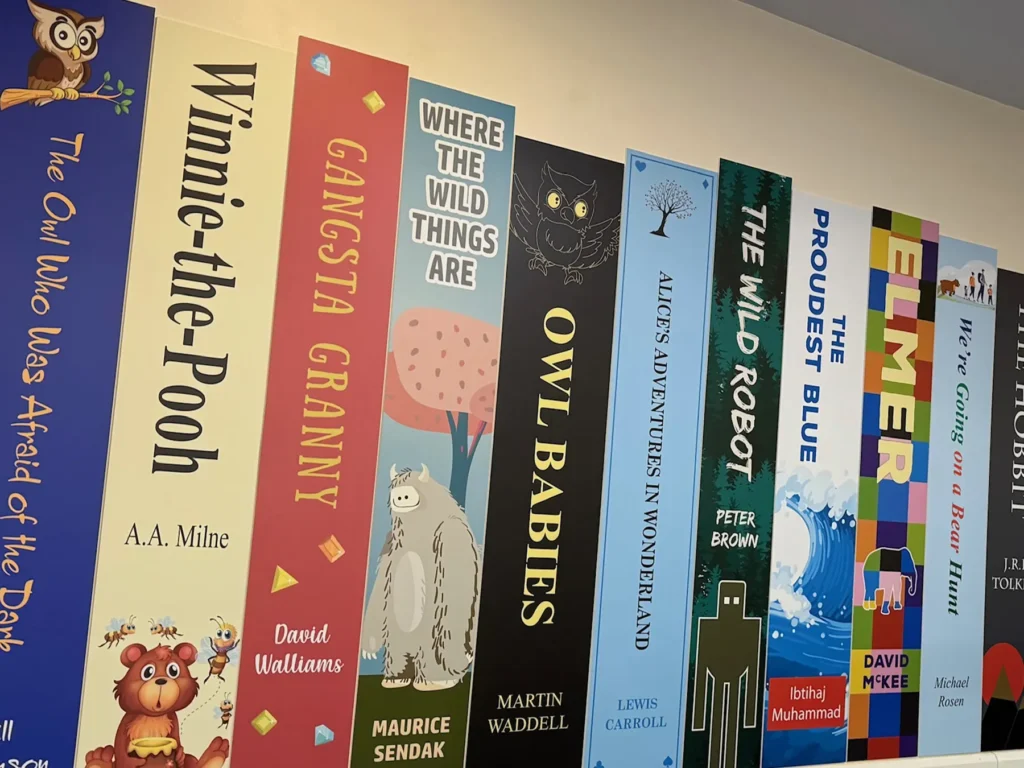 Book spine wall graphics fitted on a corridor wall of a Primary School, displaying popular primary age book titles